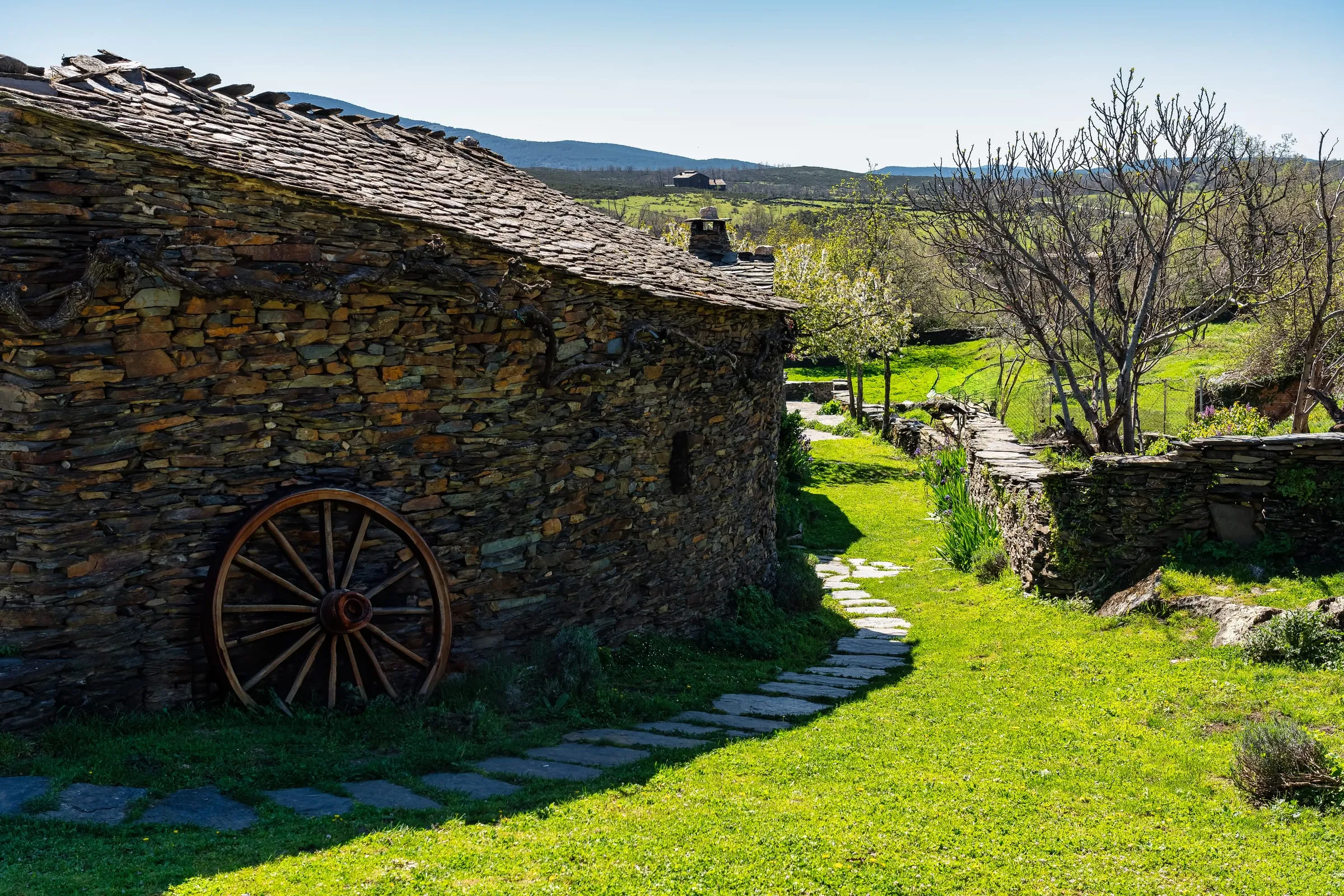 Casa antigua de piedra y pizarra junto a un prado en la sierra de Guadalajara