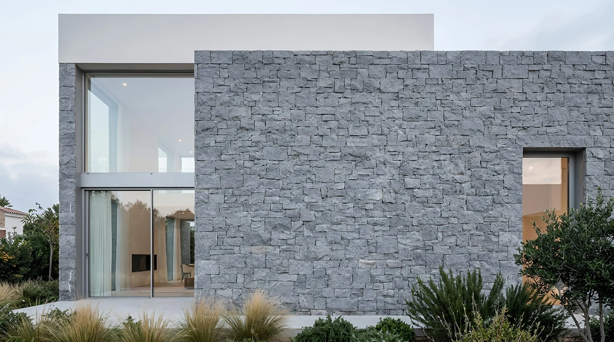 Casa contemporánea con fachada de piedra y ventanales de suelo a techo