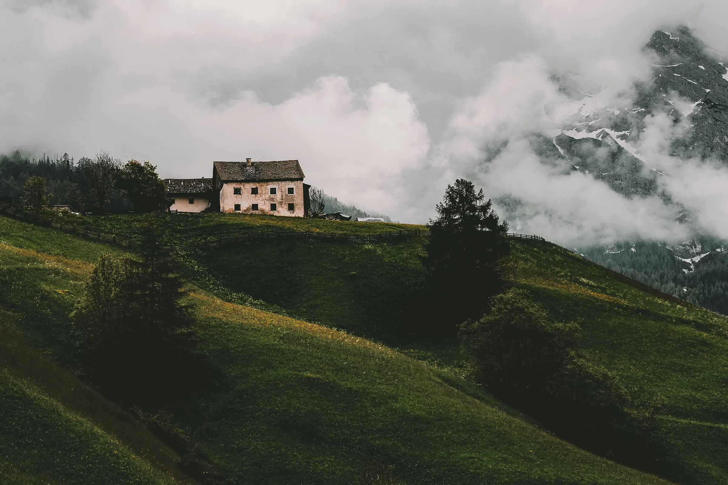 Casa en una ladera verde con niebla en la montaña