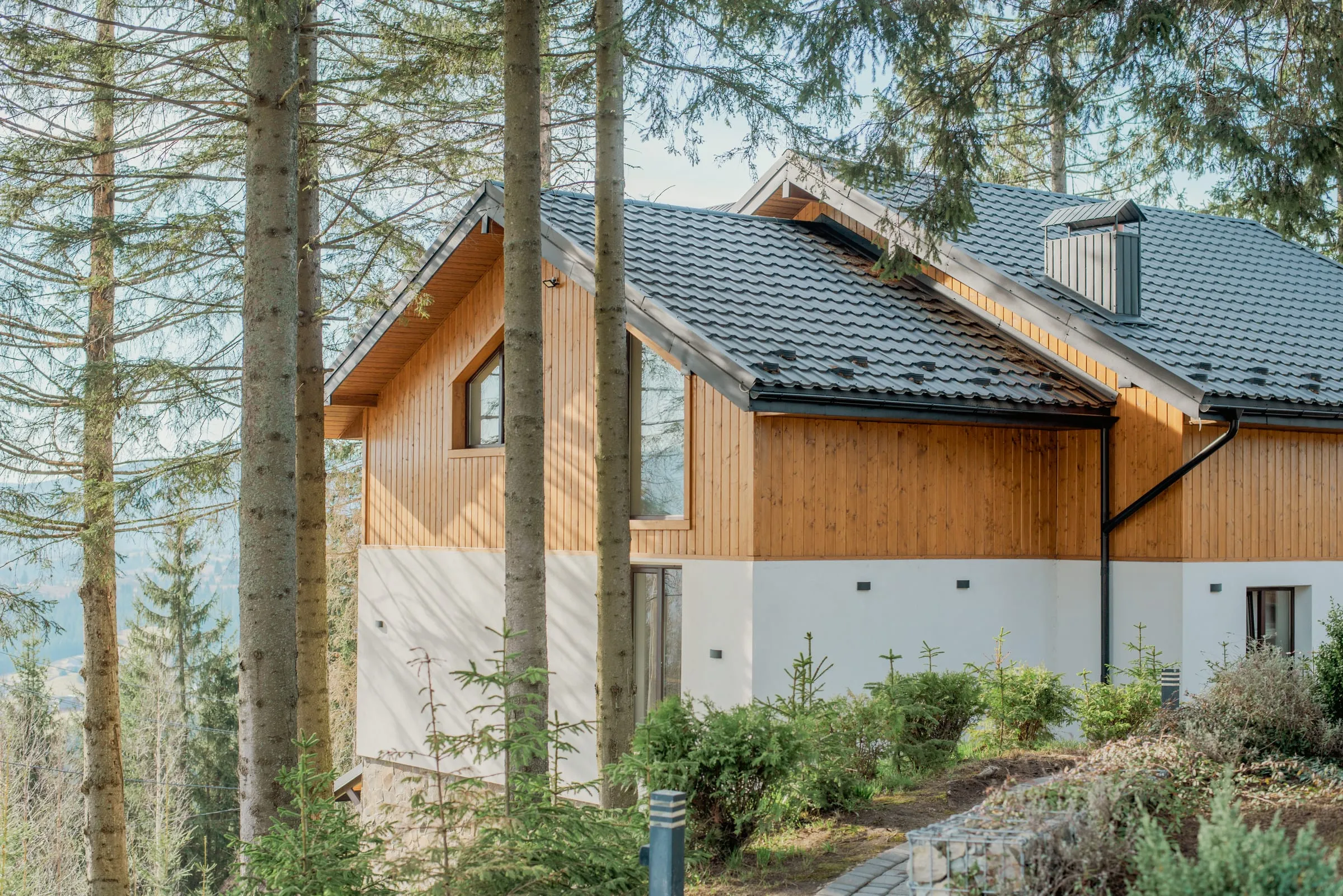 Casa moderna de madera y piedra en un entorno de montaña y bosque