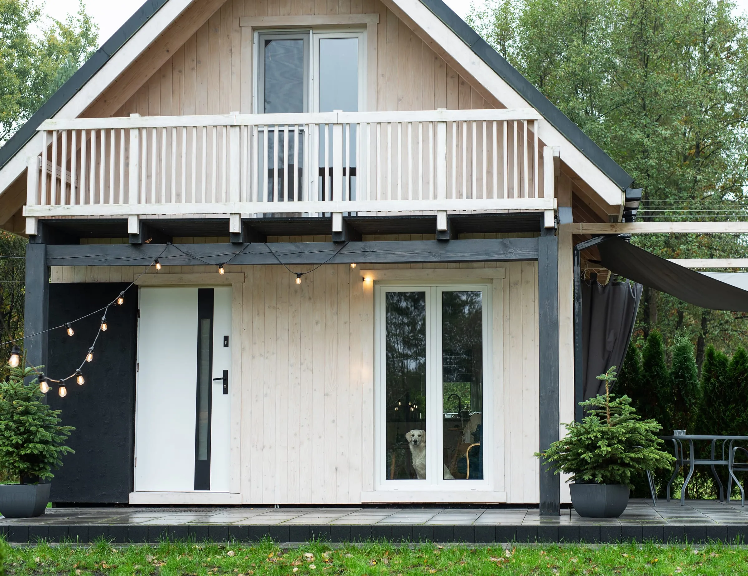 Casa pequeña de madera blanca con terraza y grandes puertas acristaladas