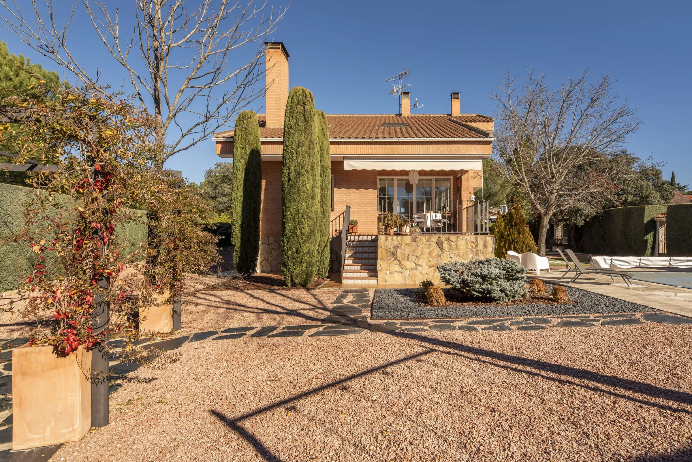 Chalet con cipreses y jardín de grava