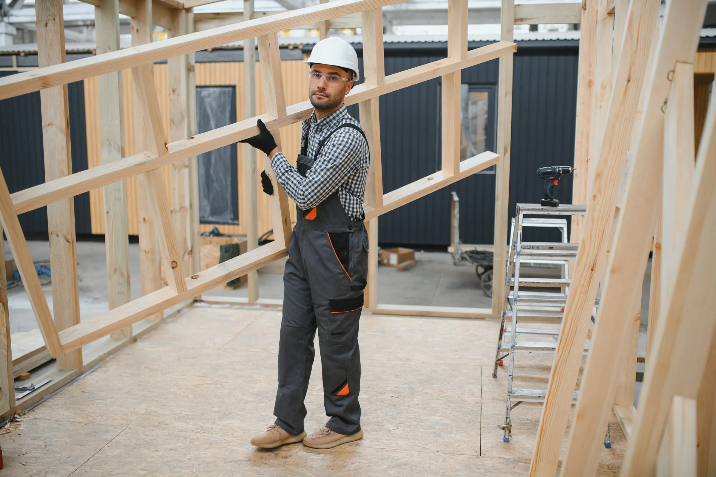 Carpintero montando el entramado de madera de una casa modular en fábrica