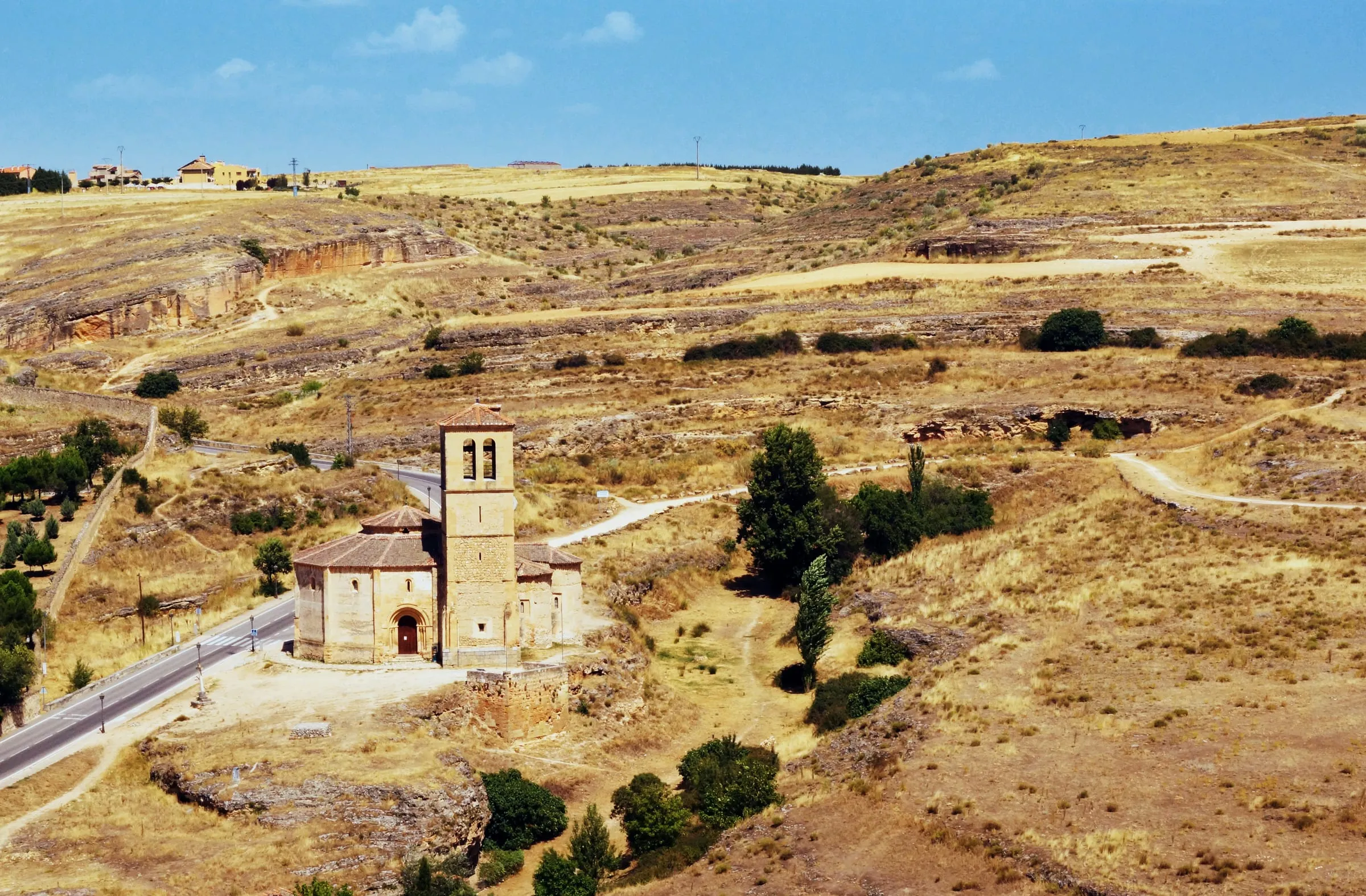 Vista aérea de una pequeña iglesia junto a una carretera en un valle de Segovia