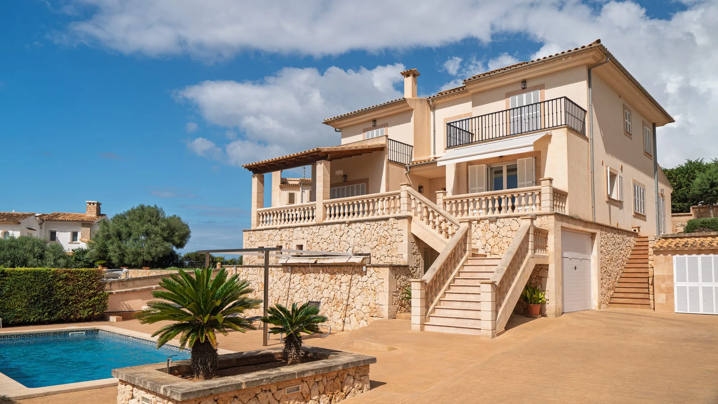 Vivienda unifamiliar de estilo mediterráneo con terrazas, palmeras y piscina